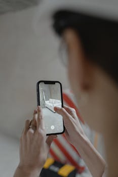 Person using augmented reality on smartphone to view furniture layout.