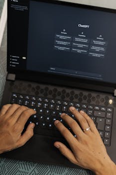 Hands typing on a laptop displaying the ChatGPT interface, showcasing AI technology.