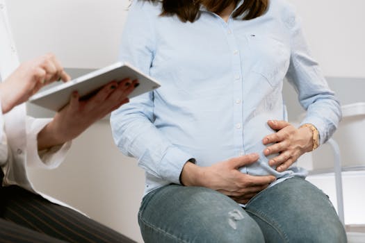 Pregnant woman attending a healthcare consultation, showcasing doctor-patient interaction.
