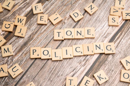 Scrabble tiles spelling 'Tone Policing' arranged on a rustic wooden surface, showcasing communication concepts.