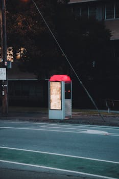 Vibrant red vending machine on an empty street at dusk, providing urban charm.